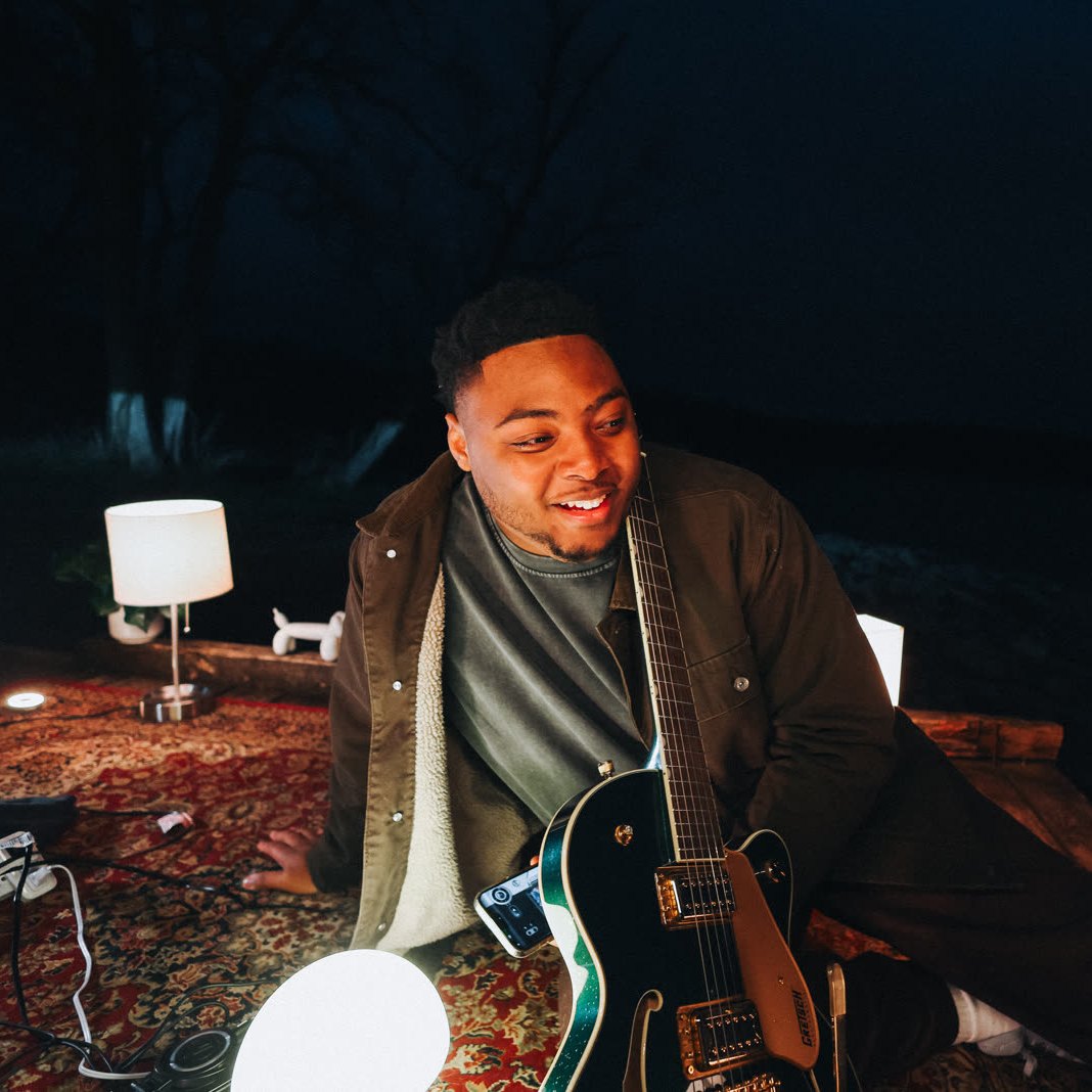 Sincer laughing with his guitar by the lake
